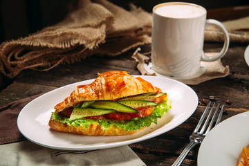 croissant sandwich with vegetbles salmon coffee