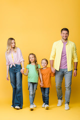 happy parents holding hands with kids on yellow