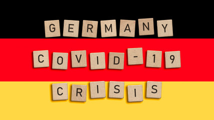 Germany Covid 19 crisis written with wooden tiles over German flag background