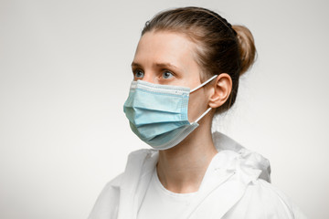 Young woman nurse in medical mask looking aside.