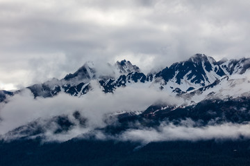 Fototapeta na wymiar Snow capped rugged rocky mountains in clouds on the Kenai Peninsula of Alaska