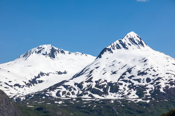 Fototapeta na wymiar Snow capped rugged rocky mountains on blue sky day on the Kenai Peninsula of Alaska