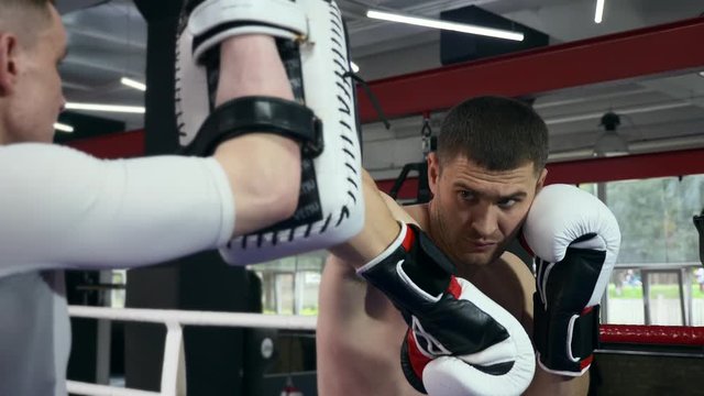 Close-up Portrait Emotional Hit on Boxer Punch Pad. Training in Boxing Ring at Urban Gym. 2x Slow motion 1/2 speed 60 fps 4K
