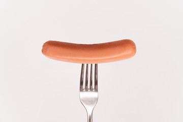 Raw frankfurter sausage on a fork isolated 