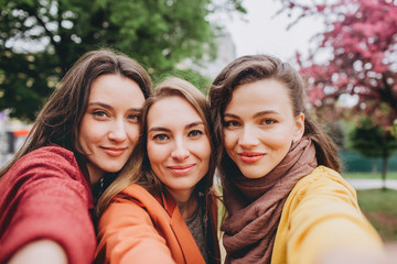 Obraz premium Best friends girls having fun, joy. Lifestyle. Beautiful young women in sunglasses dressed in the nice clothes smiling on a sunny day. photos of girls against the background of flowering trees