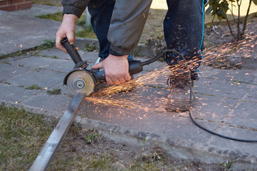 Close-up of the working process, using an electric angle grinder, they cut a metal rod and produce many sparks