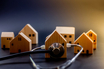 Mini wooden house with Stethoscope using as check up business financial, crisis, and property real...