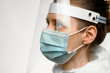close-up profile of young woman in medical mask and protective screen on her head
