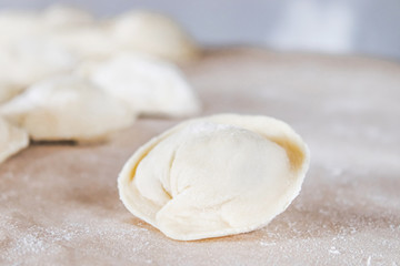 Raw dumplings with minced meat on the table. The process of making homemade dumplings.