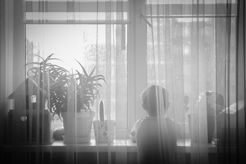 silhouette of a child looking out window