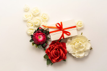 Gift box present decorations flatlay. Gift red ribbon red white flowers top view. Congratulation...