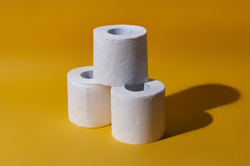 Creative still life with rolls of toilet paper, hot commodity during covid-19 and period of self isolation. Yellow background, copy space