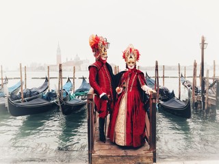 coppia in maschera per il carnevale di venezia di fronte alle gondole della laguna