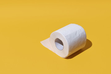 Creative still life with rolls of toilet paper, hot commodity during covid-19 and period of self isolation. Yellow background, copy space
