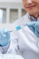 selective focus of dentist pointing with finger at toothbrush