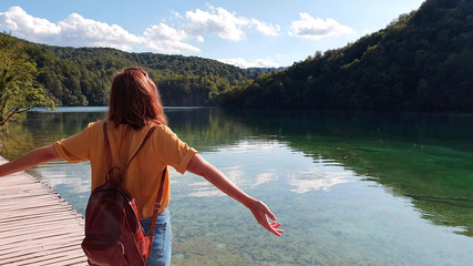 Young girl standing at plitvice lake in croatia enjoing the beautiful view and nature