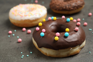 Yummy donut with colorful sprinkles on dark table, closeup