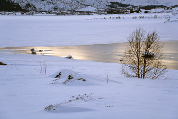 Frozen lake with snowy mountains during winter in Lapland.
