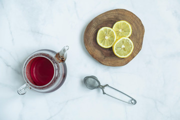 Brewed fresh tea, strainer with a sliced lemon in wooden platter on marble background. Traditional, healthy and organic beverage. Top view, flat lay.