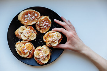 Hand is holding homemade fruit cake for breakfast on the ceramic plate. Top view. selective Focus