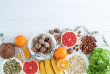 Superfoods on a white wooden background with copy space. Nuts, fruit, greens and seeds. Healthy vegan food concept