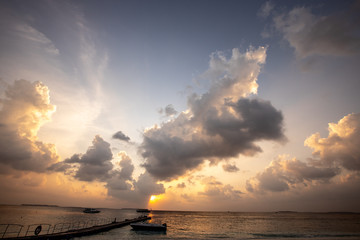 Beautiful sunset cloudscape over ocean background. Sun rays beaming through picturesque clouds above sea.
