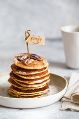 Homemade classic american pancakes with pecans and maple syrup, served with fingerfood sticks. Stack of small pancakes with bamboo brochettes on light grey background. American cuisine.