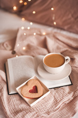 Cup of coffee with heart shape cake in bed closeup. Good morning. Breakfast. Valentines Day.