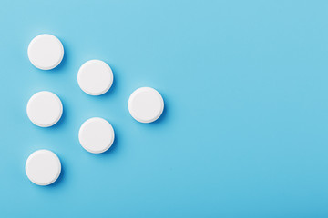 Round medicinal tablets in the shape of a triangle on a blue background, isolate.