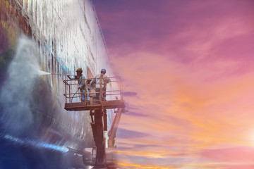 Shipyard Worker washing and cleaning in floating dry Dock worker steam cleaning a old ships hull or...