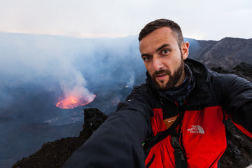 Obraz premium Democratic Republic of Congo - March 10, 2018. Tourist making selfie on top of volcano in Congo