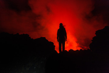 A person standing in front of the crater of volcano at night