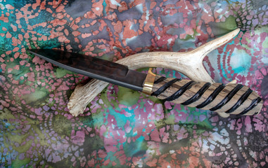 A one of a kind drop point bowie knife with hand forged damascus blade and myrtle wood handle with decorative grooves for a sure grip. Bokeh. - obrazy, fototapety, plakaty