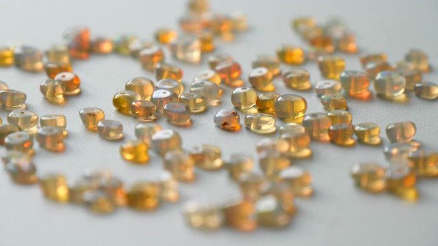 Opals gemstone from Ethiopia rotates on light background. White fire opals with rainbow like fire. Natural fire Ethiopian opal, small stones to create jewelry. Handmade stone jewelry. A pile stones.