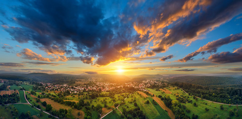 Aerial panorama of a vast landscape with a small town at a gorgeous colorful sunset with dramatic sky - Powered by Adobe