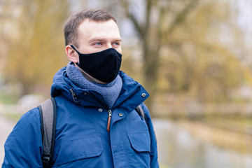 Portrait of a handsome man with blue eyes in a black protective mask during the  Covid virus quarantine period