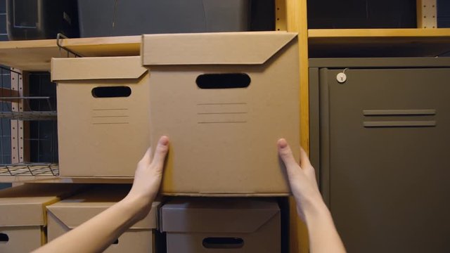 POv shot of woman putting cardboard box on shelf