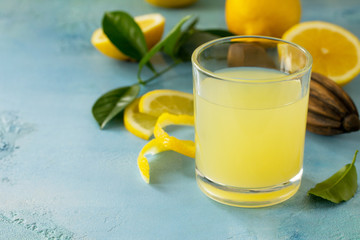 Glass of fresh freshly squeezed lemon juice on a turquoise stone or concrete table. Copy space.