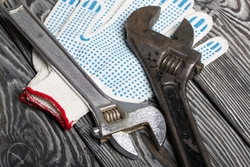 Two adjustable spanners of different sizes and colors and work gloves. Lie on brushed pine boards....