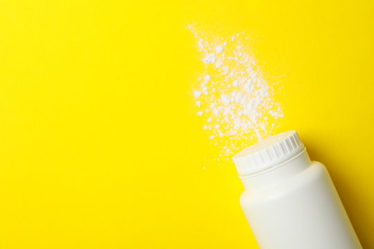 Blank bottle of talcum powder on yellow background, space for text