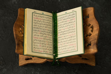 The holy book Quran or Koran on the wooden lectern with rosary and date fruits.