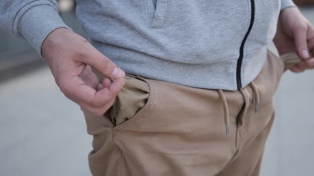 young man turns out his pants pockets,empty pockets and no money,bankruptcy and poverty,financial crisis,depression of new generation,lack of work,4K,caucasian