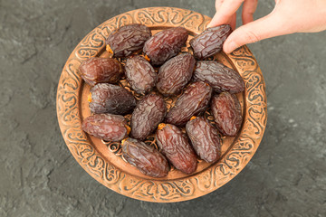 Dried date fruit or Hurma in the copper plate on the black background for muslim Ramadan tables concept.