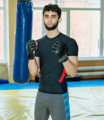 Serious Asian mixed martial artist in gloves looks at the camera before a great workout.