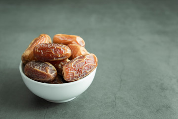 Raw date fruit ready to eat in porcelain bowl on concrete background. Traditional, delicious and healthy ramadan food.