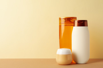 Blank cosmetic bottles on beige background, space for text