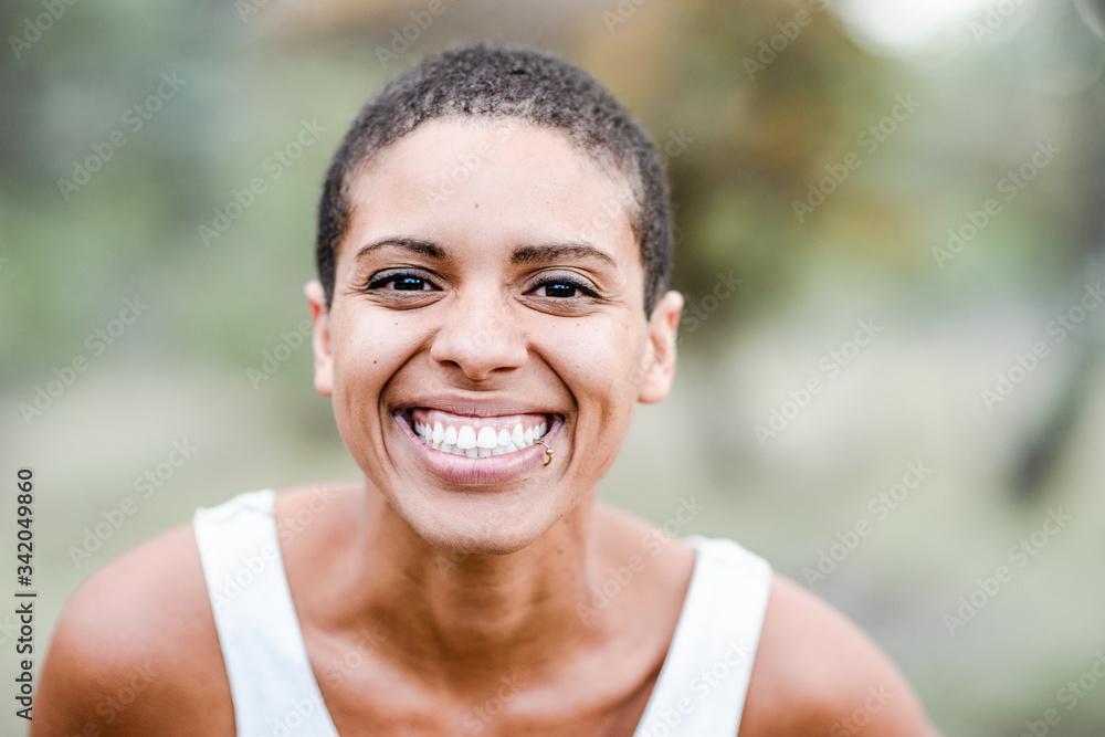 Wall mural portrait of a smiling young black woman with shaved head