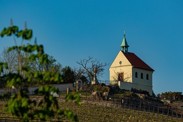 Prague, Troja / Czech Republic - April 21, 2020: Chapel of St Claire built in 17th century standing on a hill surrounded by a vineyard. Sunny spring evening with clear blue sky. 