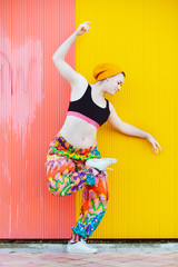 Millennial gay woman standing on a ballet pose in the street at colorful urban background. Strong feminist woman as symbol of progress. Lgbt community and gay pride lifestyle. Dance and art concept.