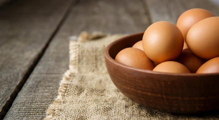 eggs in a clay plate on burlap and on an old wooden background. copy space.